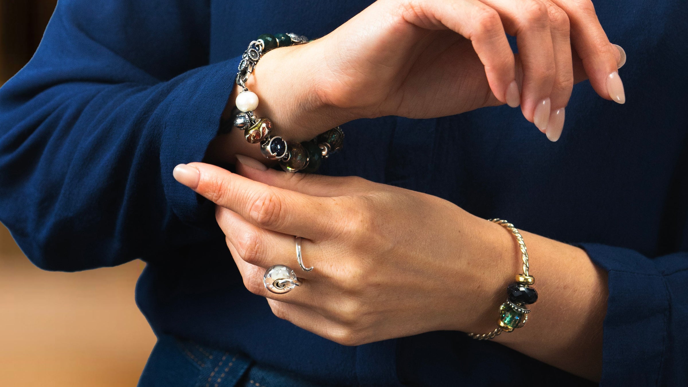 Model with blue shirt wears sparkling christmas bracelets and silver ring with bead